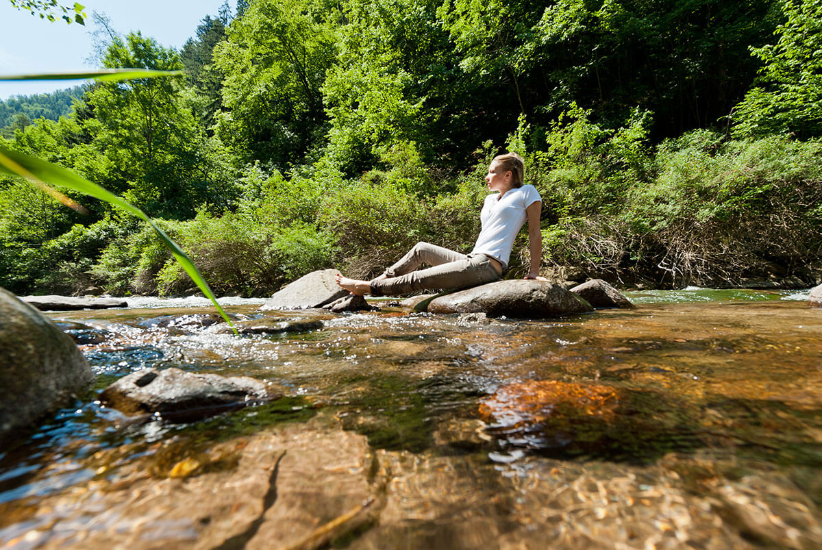 Donna che si rilassa su una pietra vicino al ruscello - Hotel Gasthof zur Sonne
