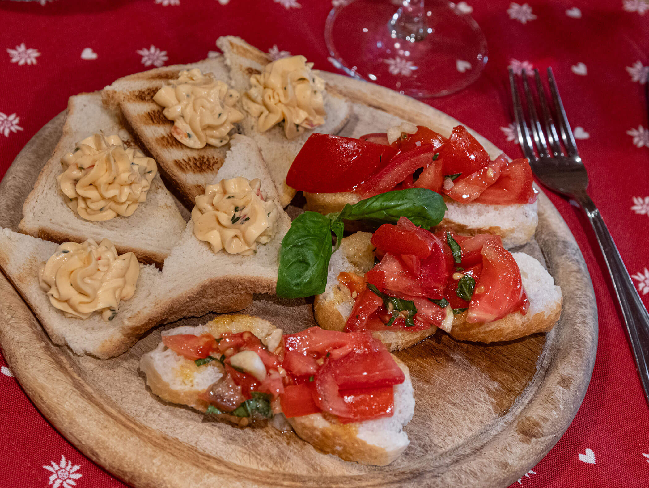 Bruschetta con pomodoro e pane con crema spalmabile, serviti su un piatto di legno. - Hotel Zur Sonne
