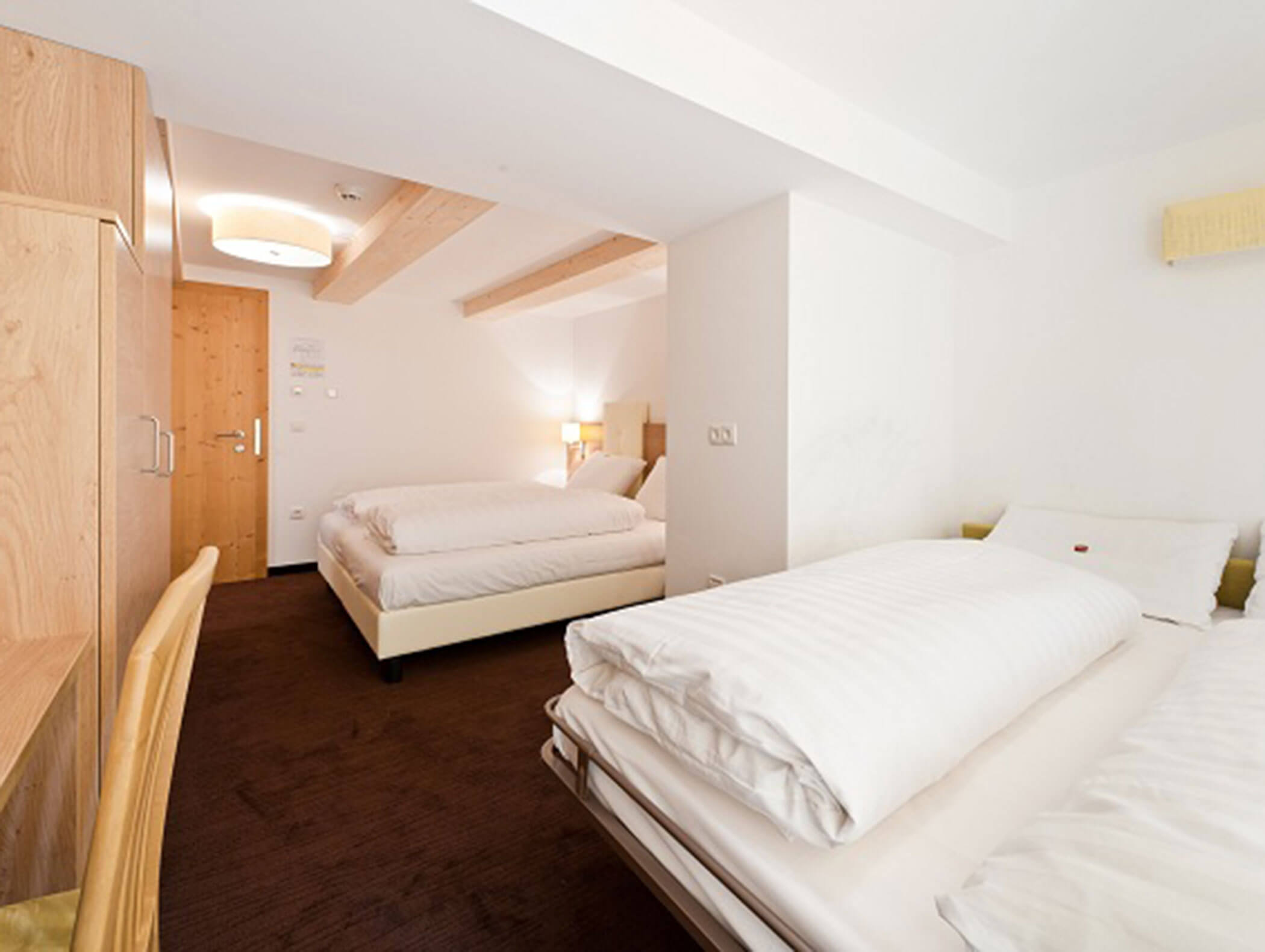 Camera d'albergo luminosa con due letti, mobili in legno, pareti bianche e moquette marrone. - Hotel Zur Sonne